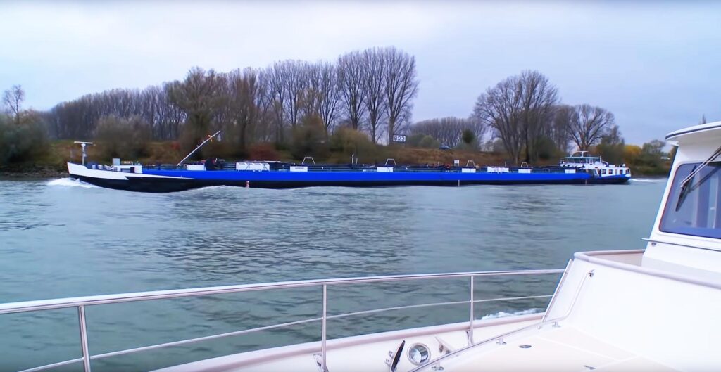 Venture II with a blue barge on the river Rhine.