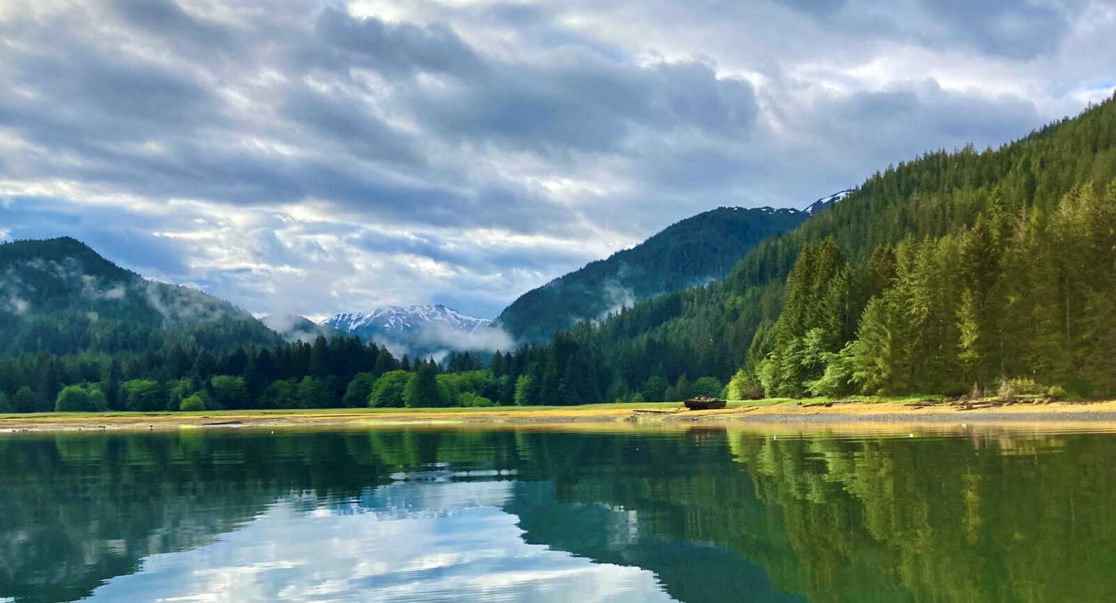 beautiful mirror reflection of a lake with trees and a snowy mountain. Camp Cougan Bay just south of Sitka.